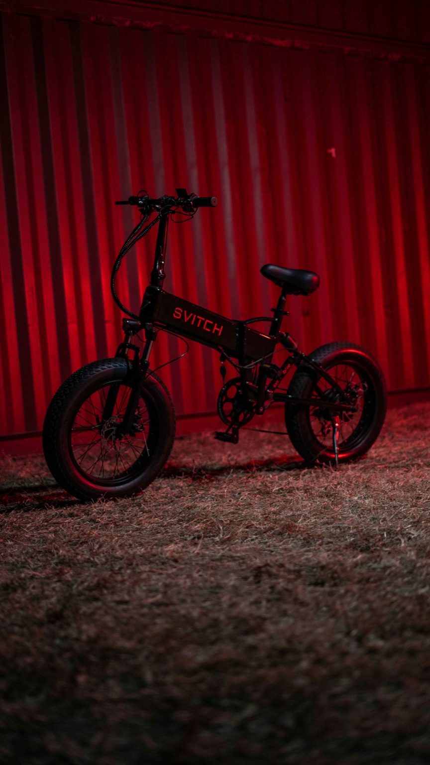Compact folding-style e-bike parked in dramatic red lighting